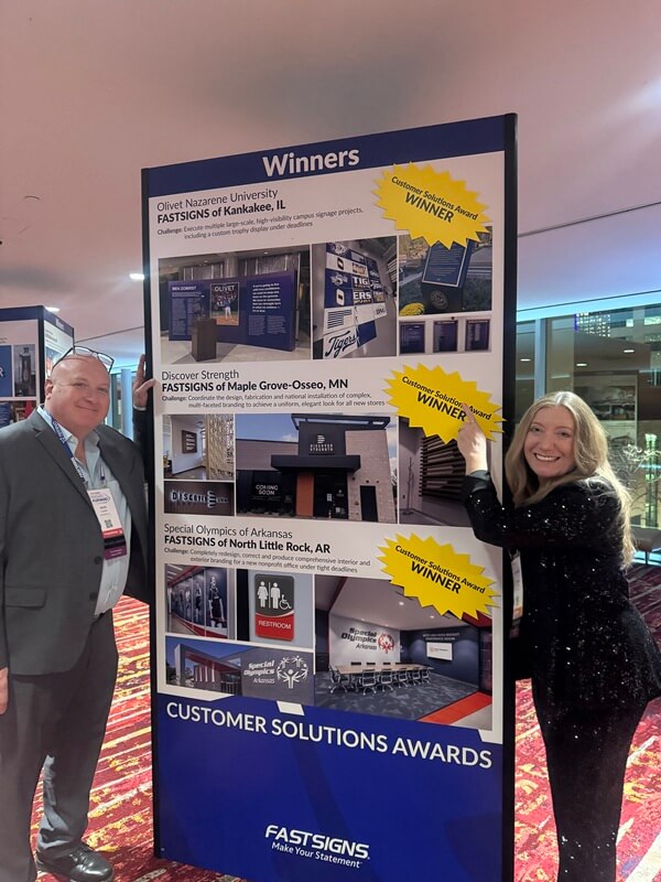 An image of the owners next to the FASTSIGNS Cares winners.